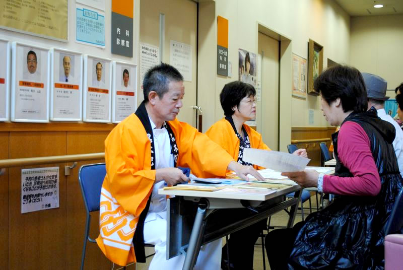 オレンジの法被を着て受付をするスタッフと受付を受ける女性