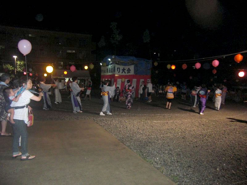 盆踊り大会でやぐらを中心に踊る大勢の人たち