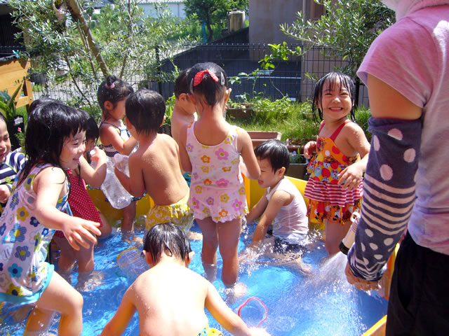 青い簡易プールで遊ぶたくさんの園児