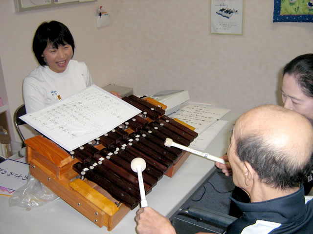 音楽療法士が弾く電子ピアノに合わせて木琴を演奏する患者